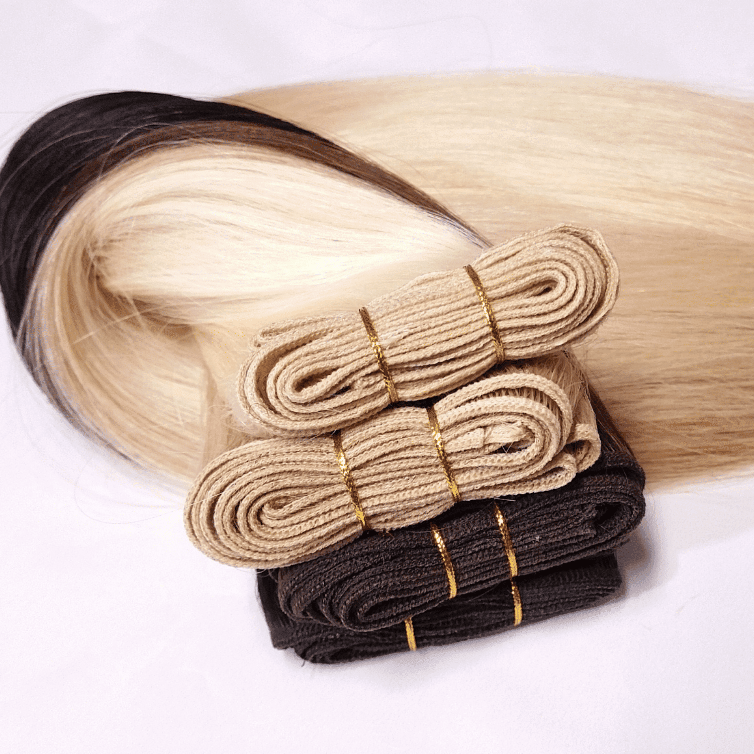 Bundles of blonde and brown hair extensions on a white background.