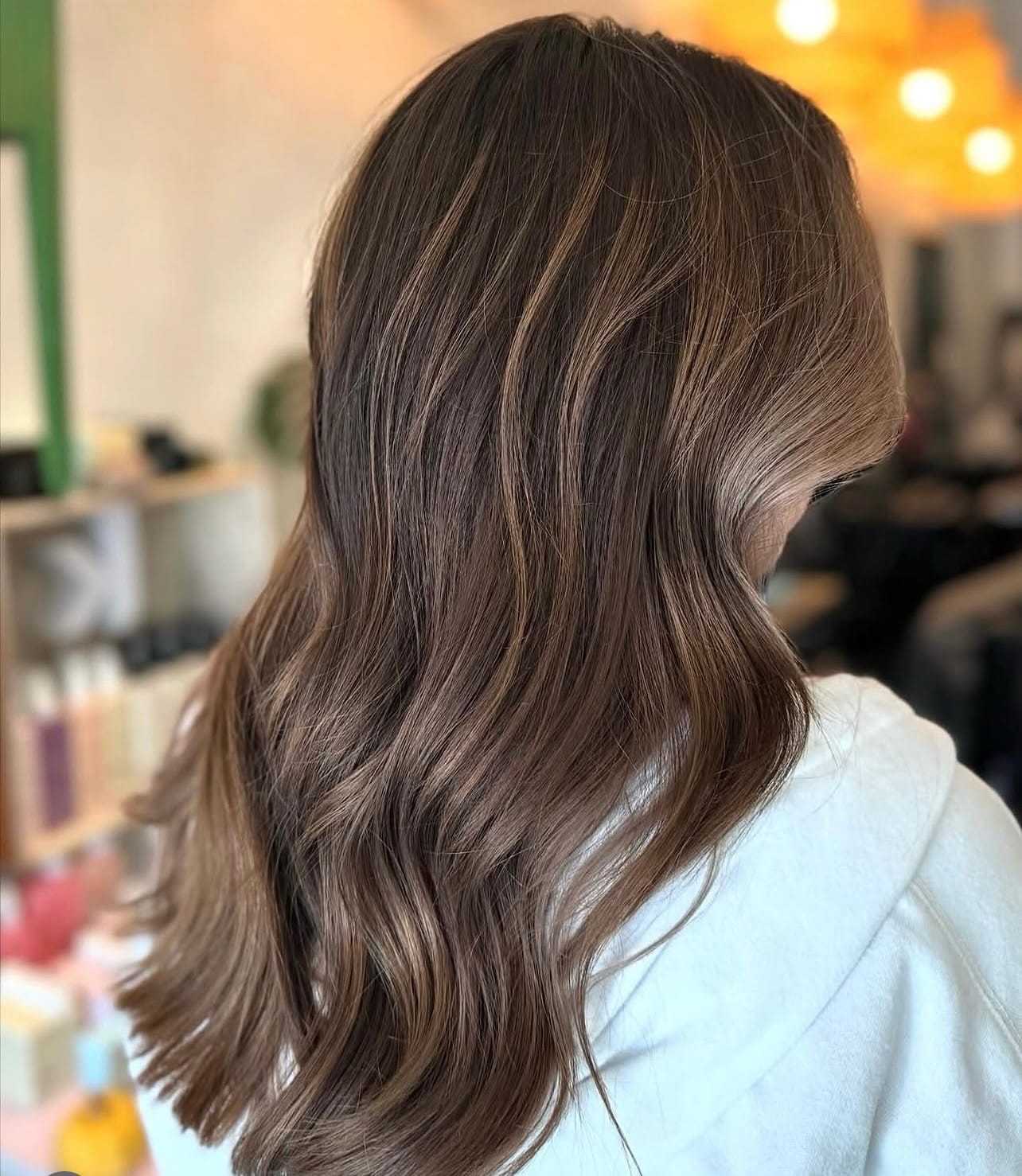 Wavy brown hair with highlights in a salon setting.