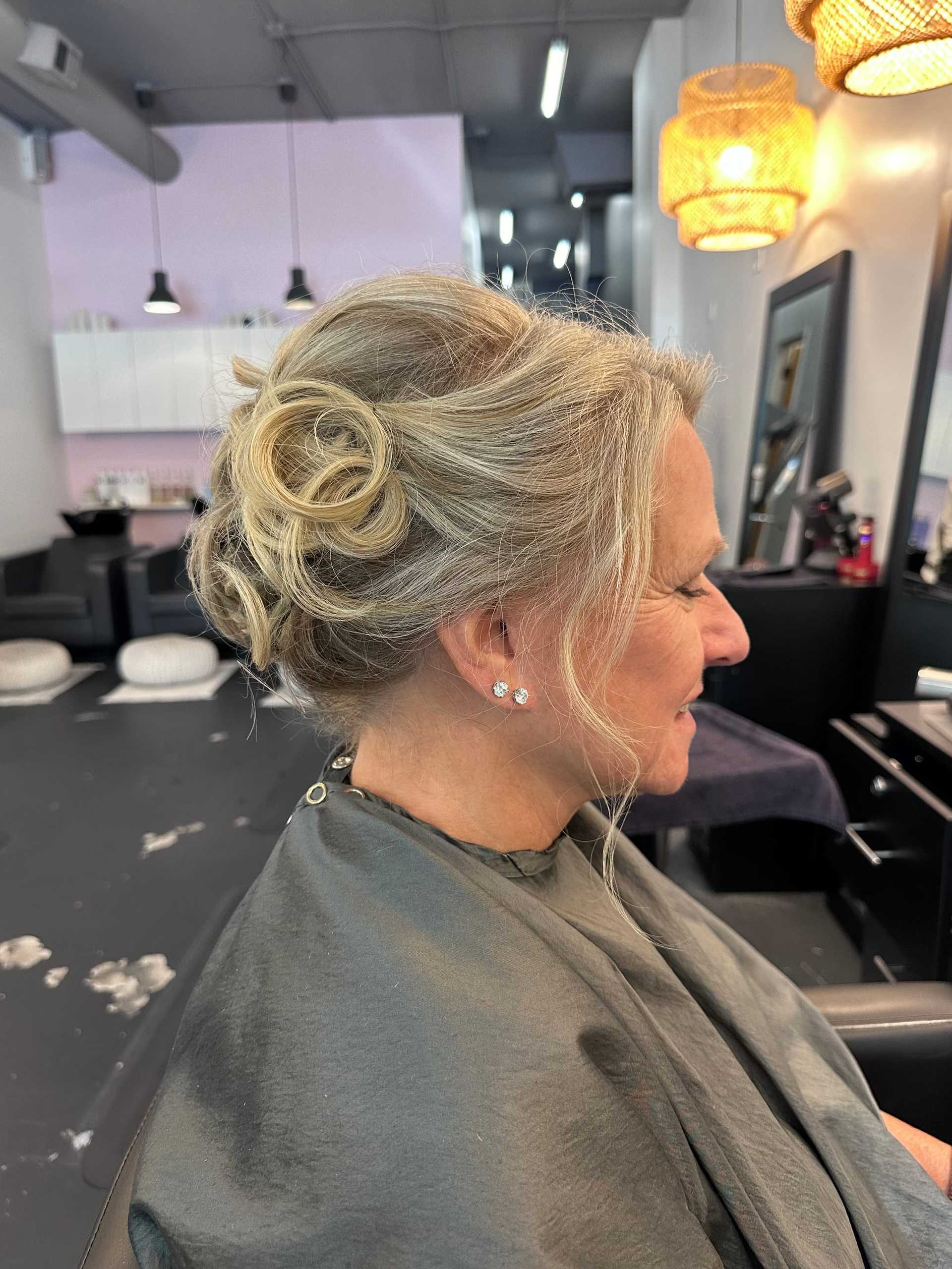Elegant updo hairstyle on a seated woman in a modern hair salon.