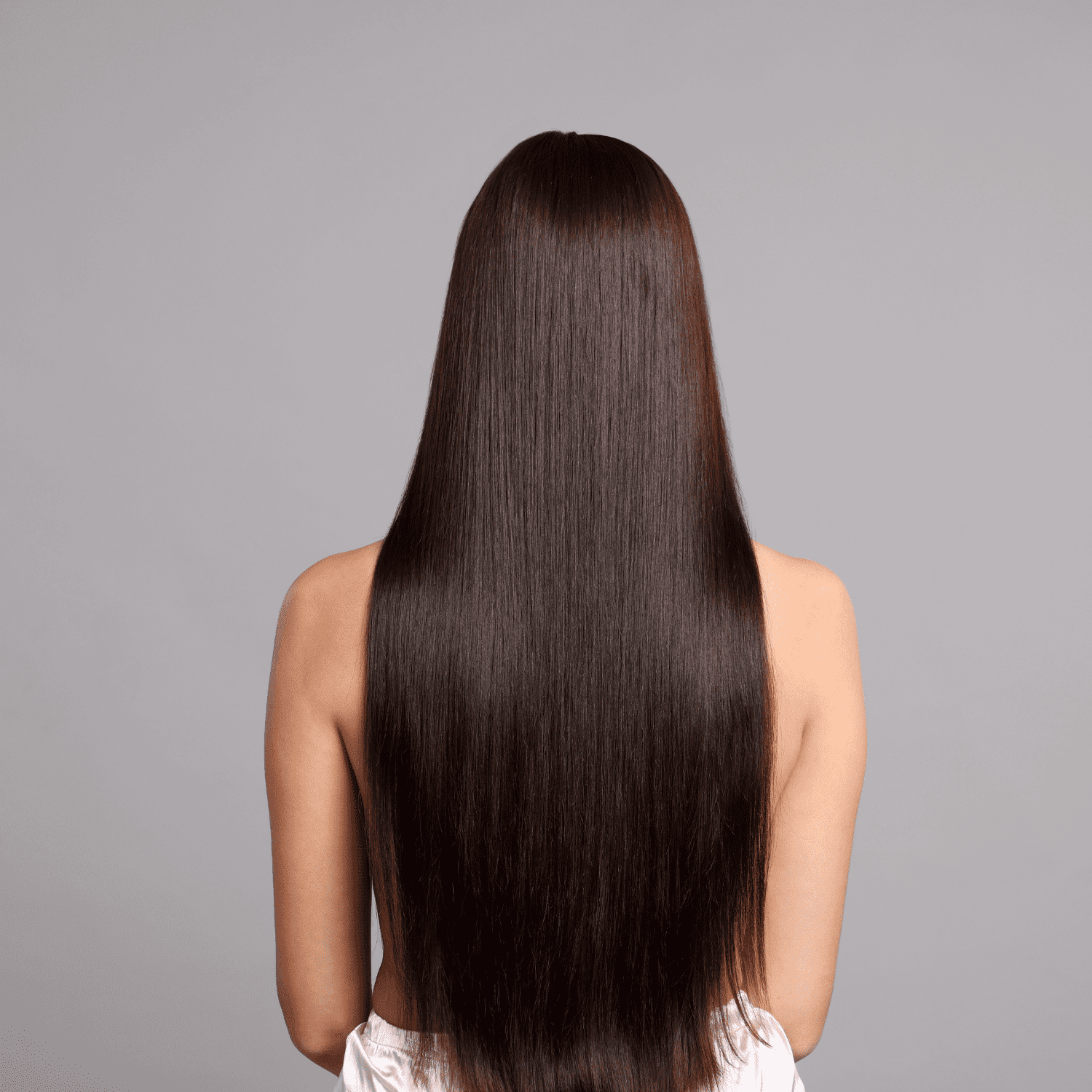 Smooth, shiny long brown hair cascading down a woman's back against a neutral background.