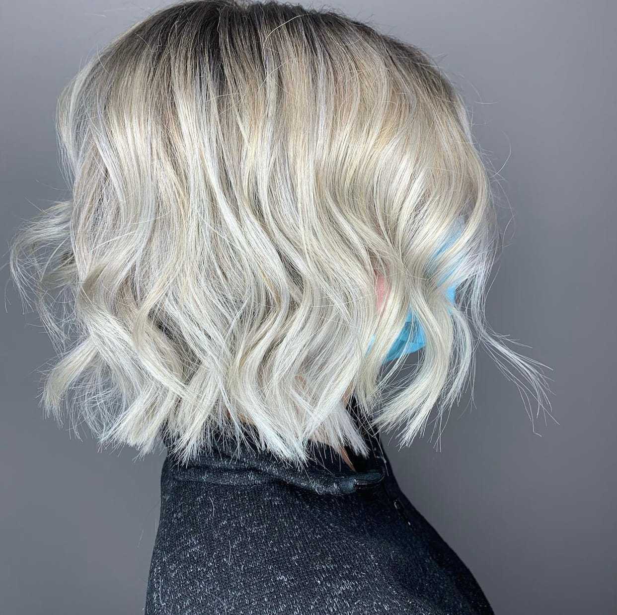 Wavy blonde bob hairstyle against a gray background.