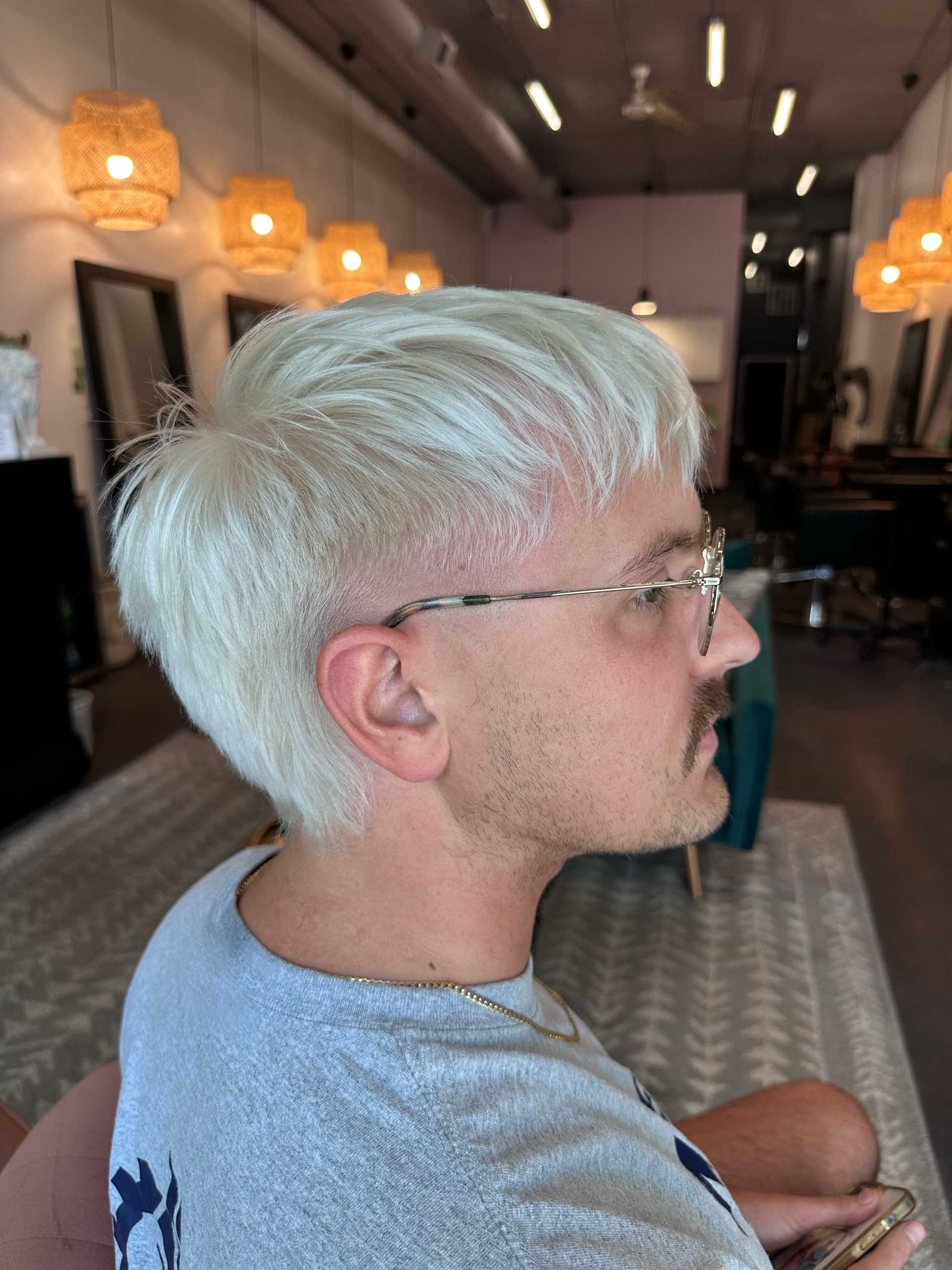 Short-haired person with glasses in a stylish, modern salon.